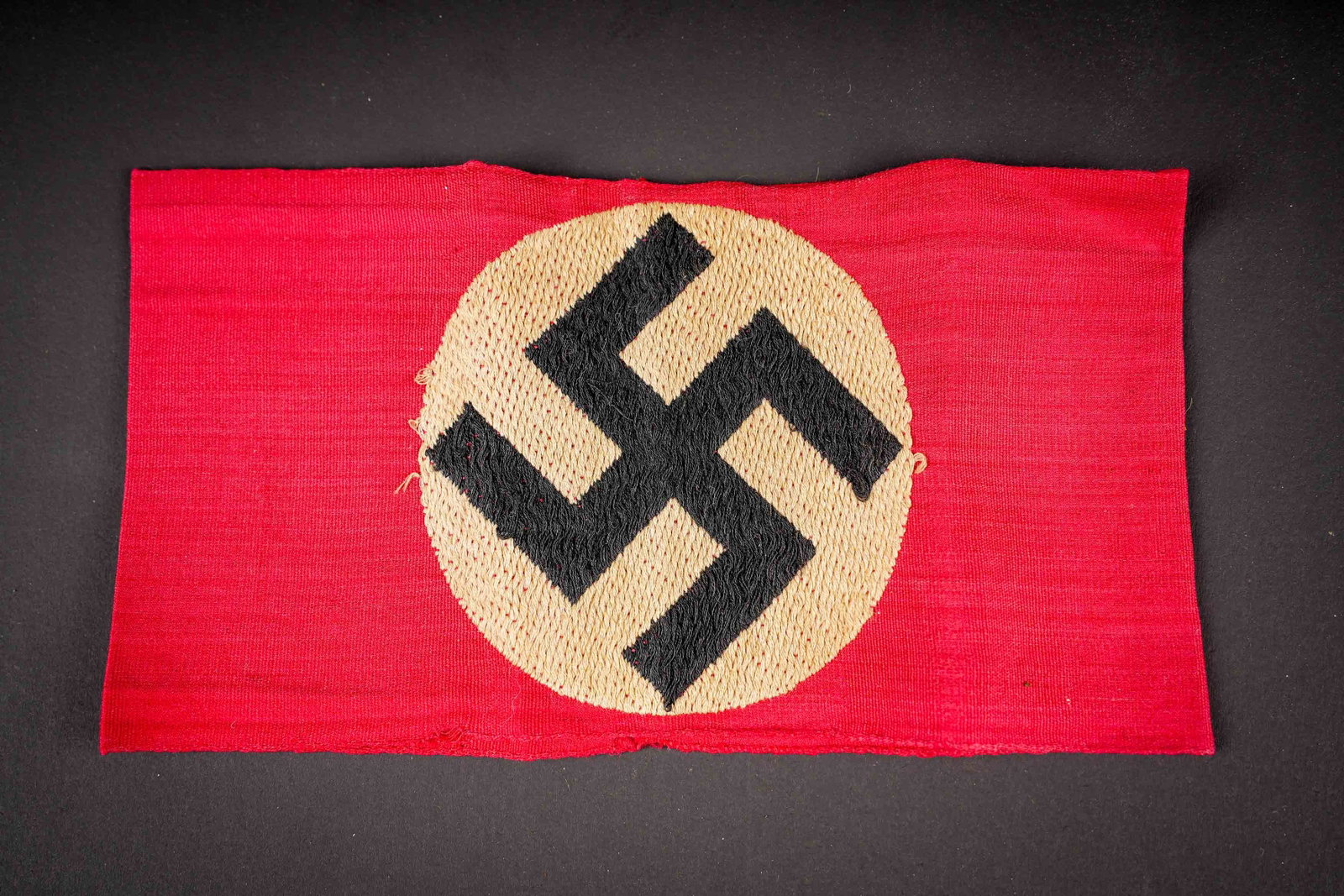 Brassard allemand. German armband.: Brassard allemand. En tissu coton rouge. Insigne national brode directement sur la bande de tissu rouge. Sans marquages visibles. A noter une certaine usure et patine de la piece, ainsi que quelques