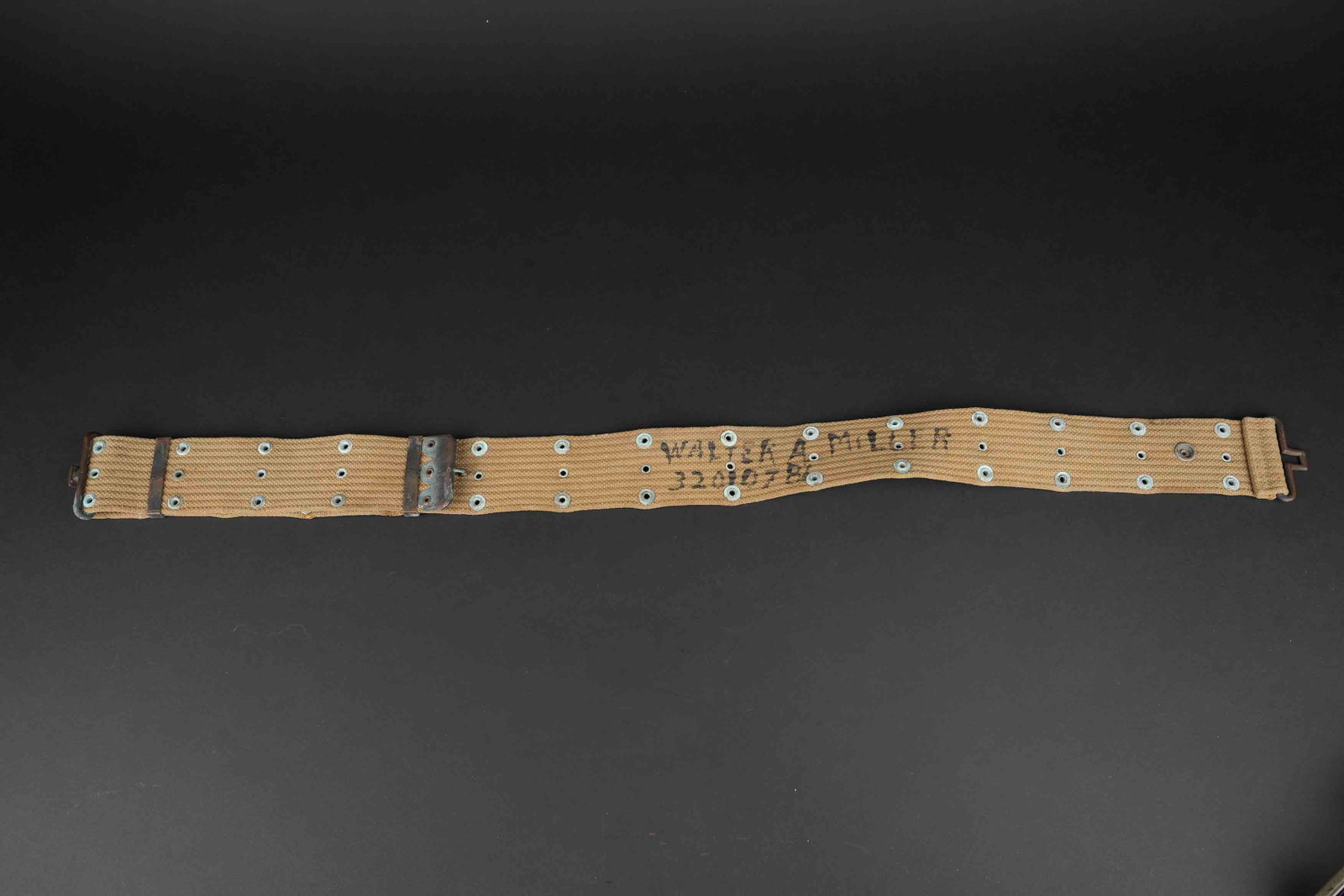 Ceinturon M36 nominatif. US named M36 belt: Ceinturon M1936 nominatif. En forte toile OD. Bouclerie en laiton, partiellement oxyde. Les marquages fabricant sont illisibles. Beau marquage US visible. Indication nominative peinte Walter A Miller 