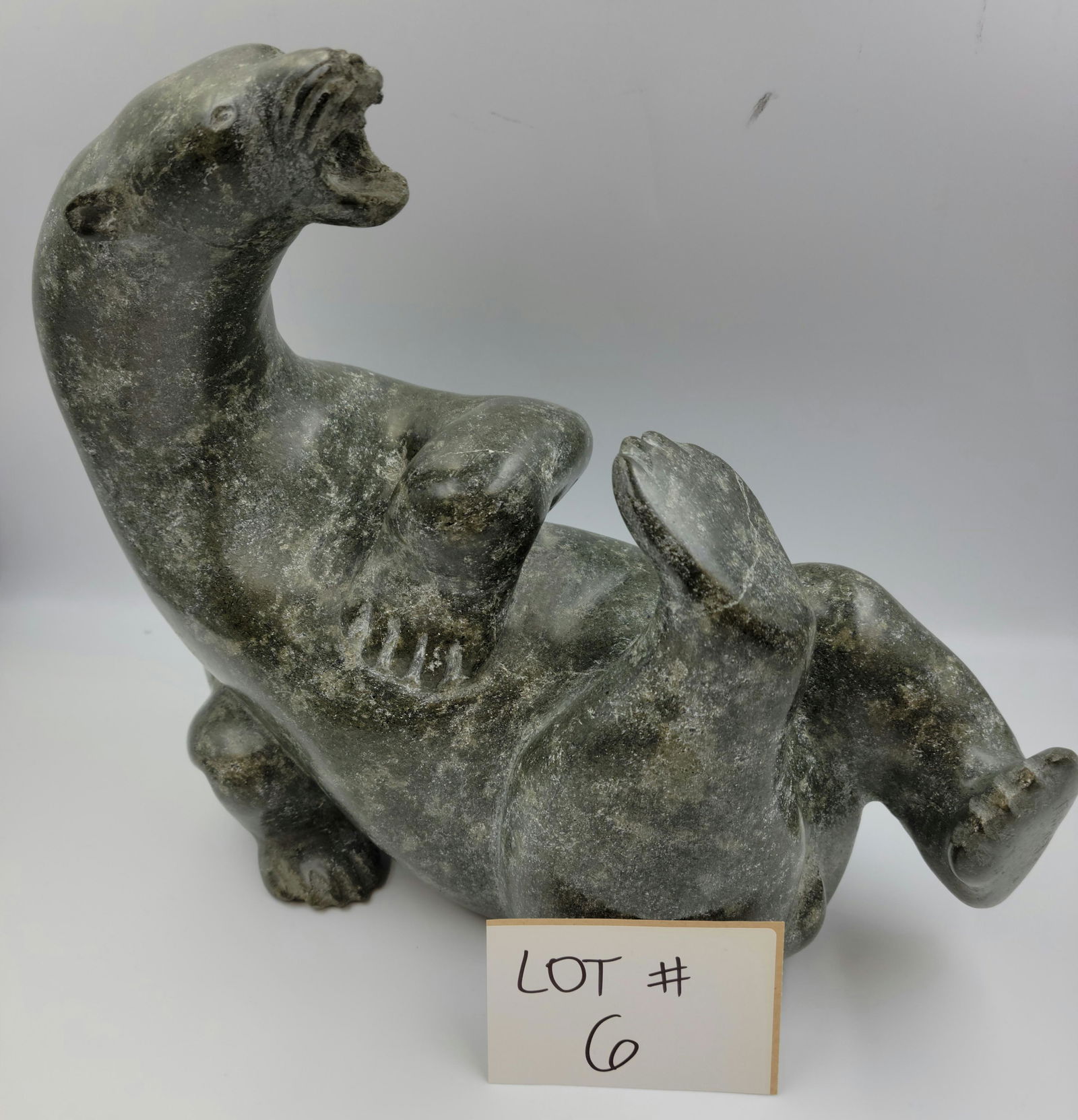 Towatuga Sagouk, (1934-) Frobisher Bay / Iqaluit, E7-826: A delightful stone carving: Playful Polar Bear. Beautifully veined stone overall, bears in a reclined position. Partial Igloo sticker underside & signed to his foot. Size: 10.5”x13”x5&rdqu