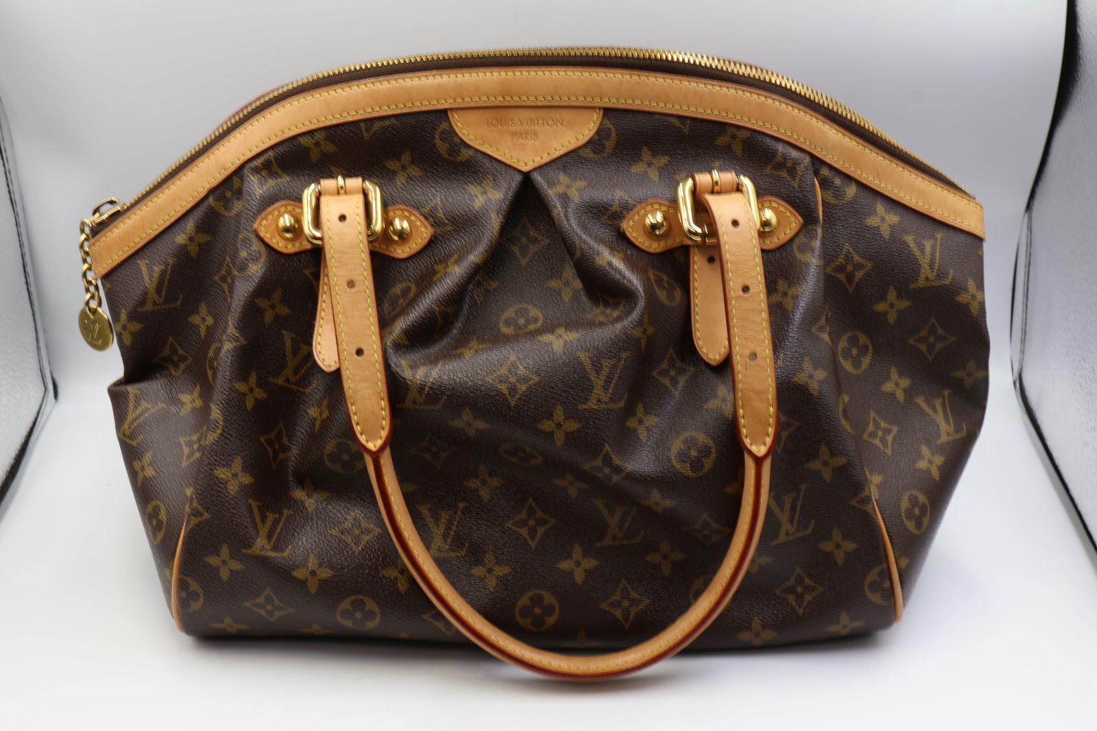 Louis Vuitton Tivoli GM Shoulder Bag: Louis Vuitton Tivoli GM shoulder bag in brown monogram coated canvas. Brown canvas interior. 13" W × 11" H. Gold-plated hardware. Brown leather double handles. Zip closure. Presented with original