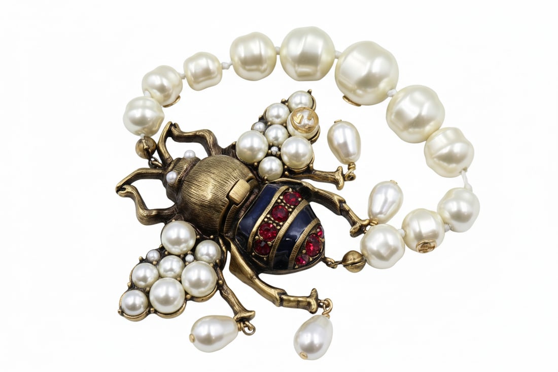 Vintage Gucci Crystal Faux Pearl Bee Bracelet: Vintage Gucci bee bracelet in gold-tone metal with crystal and faux pearl bee motif on faux pearl bracelet. Measures 22cm. Stamped Gucci. Presented with original Gucci bag and box. Excellent vintage