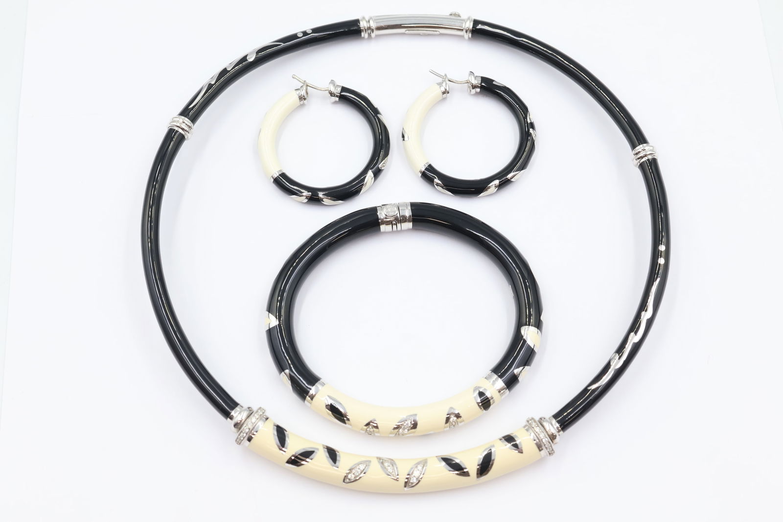 Black & White Enamel Diamond Jewellery Set: Jewellery set comprising hoop earrings, bangle bracelet, and choker necklace in black and white enamel panels with pavé diamond leaf accents. Presented with original box.
