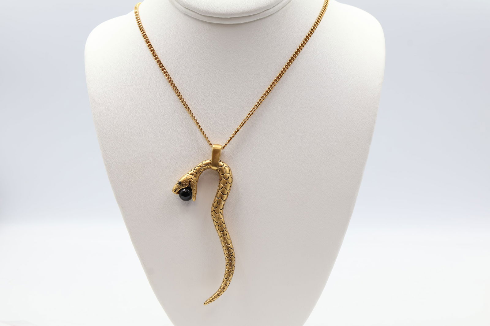 YSL Gold-Tone Serpent Pendant & Chain: Yves Saint Laurent serpent pendant in yellow gold-plated metal set with a black glass stone. 17-inch circle link chain with lobster clasp. Signed Yves Saint Laurent.