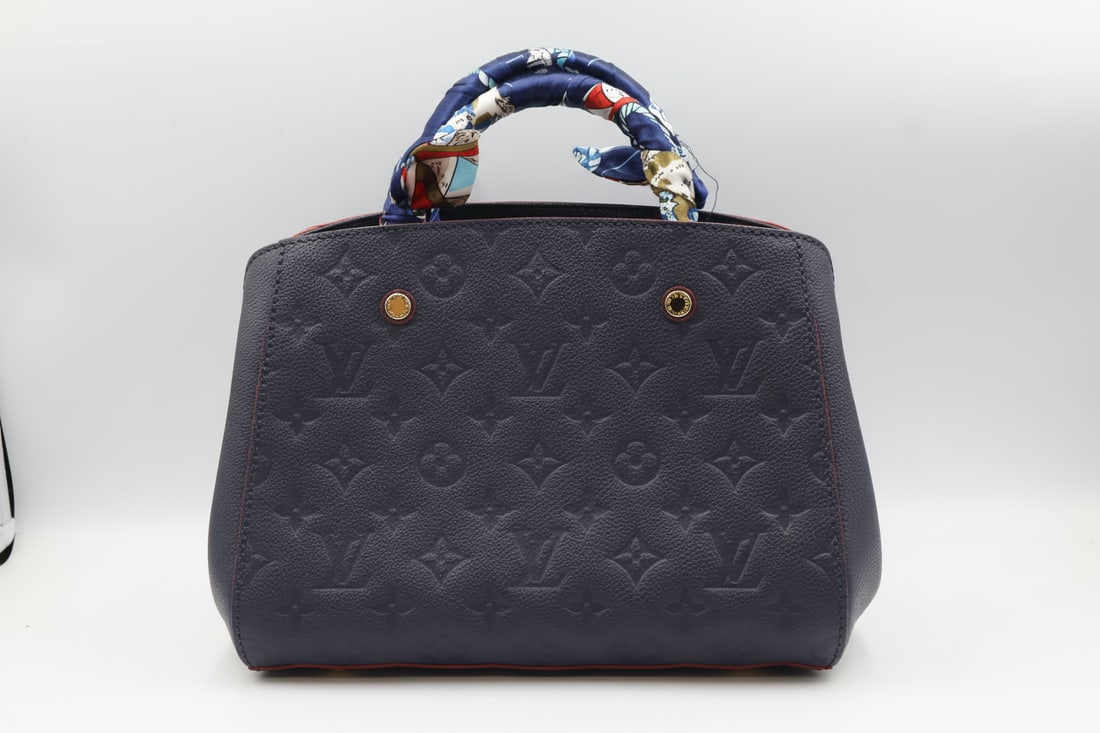 Louis Vuitton Montaigne BB in Marine Rouge Monogram Empreinte Leather: Louis Vuitton Montaigne BB in Marine Rouge Monogram Empreinte leather. This refined handbag features navy blue Monogram Empreinte leather with red leather trim and brass hardware. It includes dual