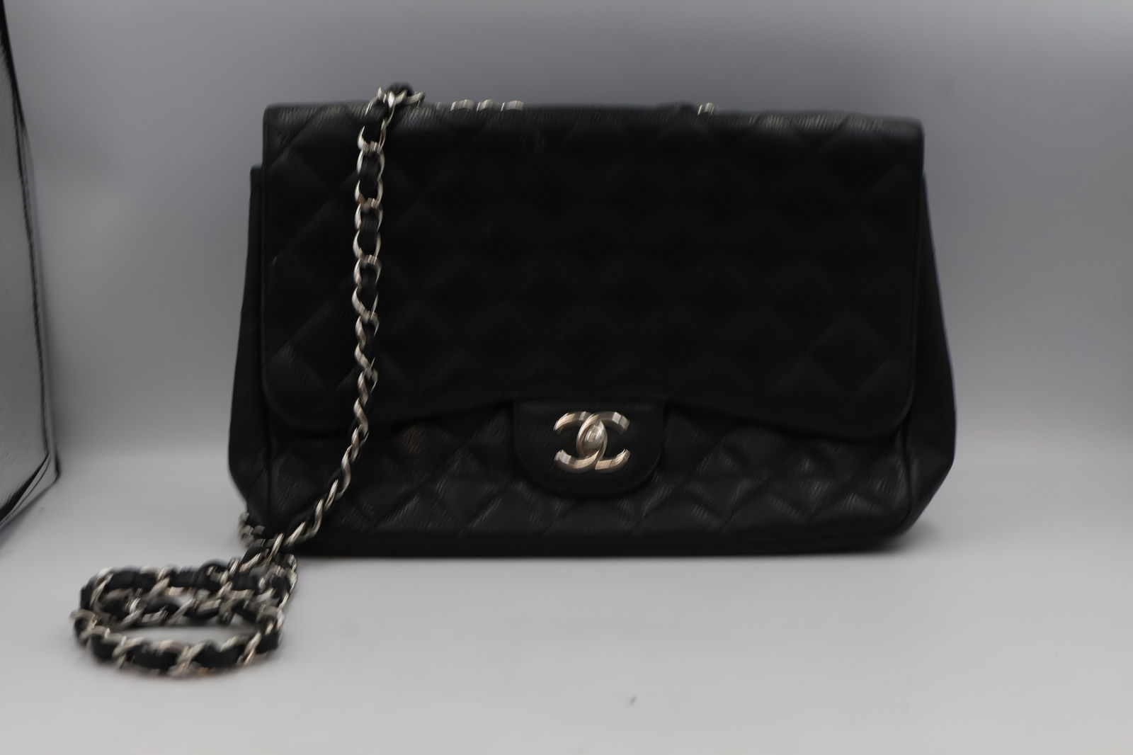Chanel Classic Flap — Black Caviar Leather: Chanel Classic Flap handbag in black caviar quilted leather. Dimensions: 30 × 19.5 × 10cm (Large/Jumbo). Interwoven silver toned chain and leather strap. CC turn-lock closure. UV date code tag