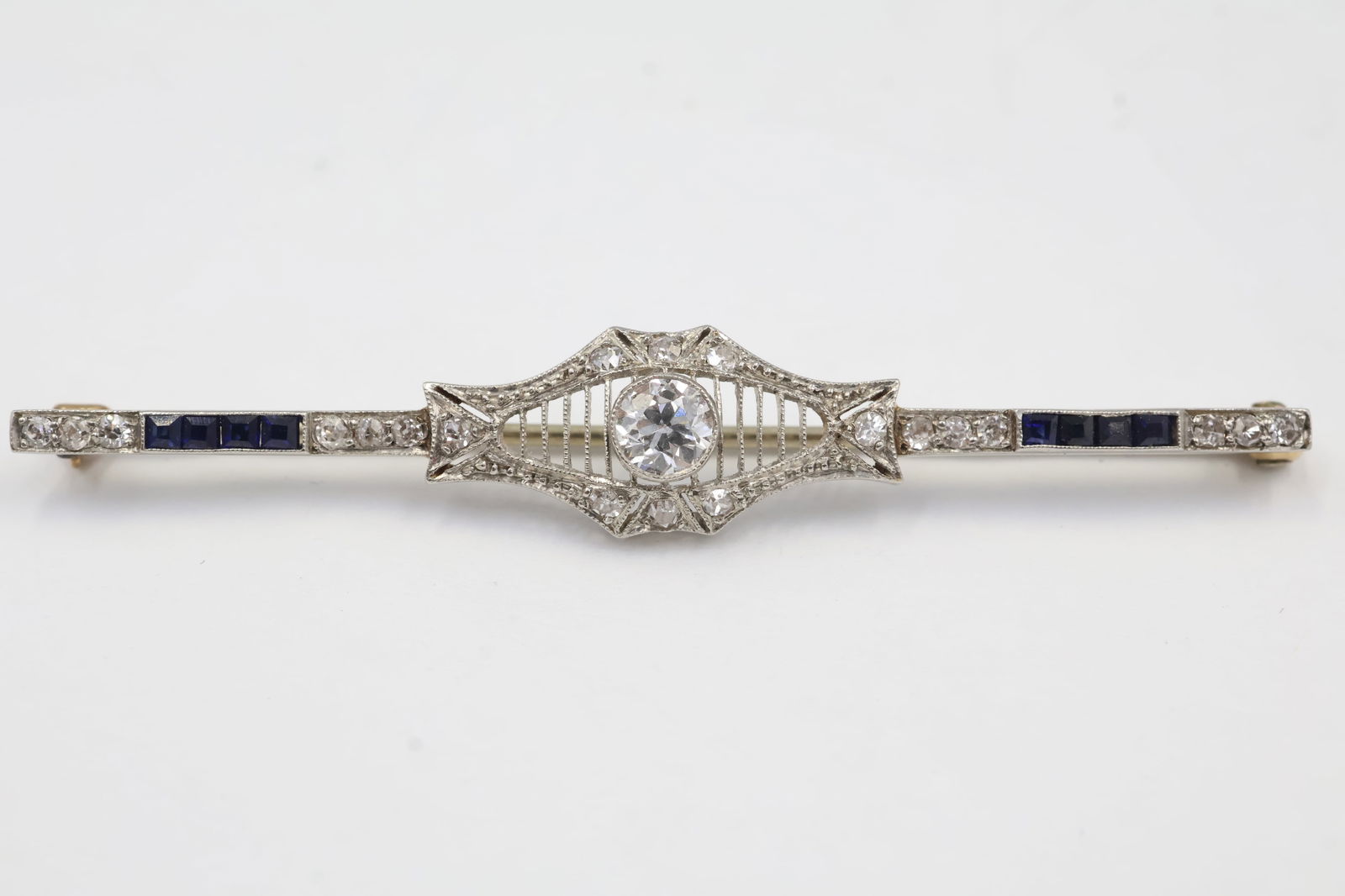 14k White Gold Bar Brooch – Square Sapphires & Diamond Centerpiece: This elegant vintage-inspired bar brooch is crafted in polished 14k white gold and measures 2 inches in length. The piece features a striking arrangement of 8 square-cut sapphires, 18 petite accent di