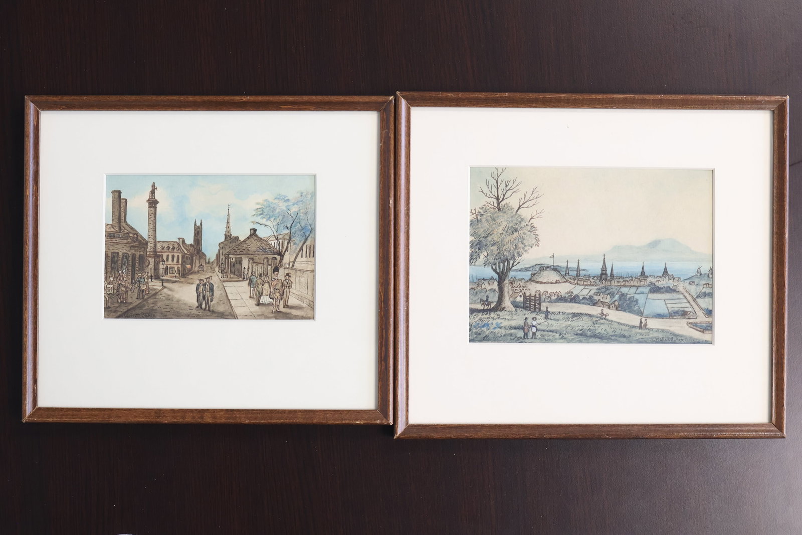 Walter Baker, Canadian (1859-1912): Complimentary pair of watercolours on paper one showing figures on a hill overlooking a village, Signed l/r, Image size: 4.5 x 6 1/4 inches (Frame size: 9 x10 inches). One showing well cladded figures