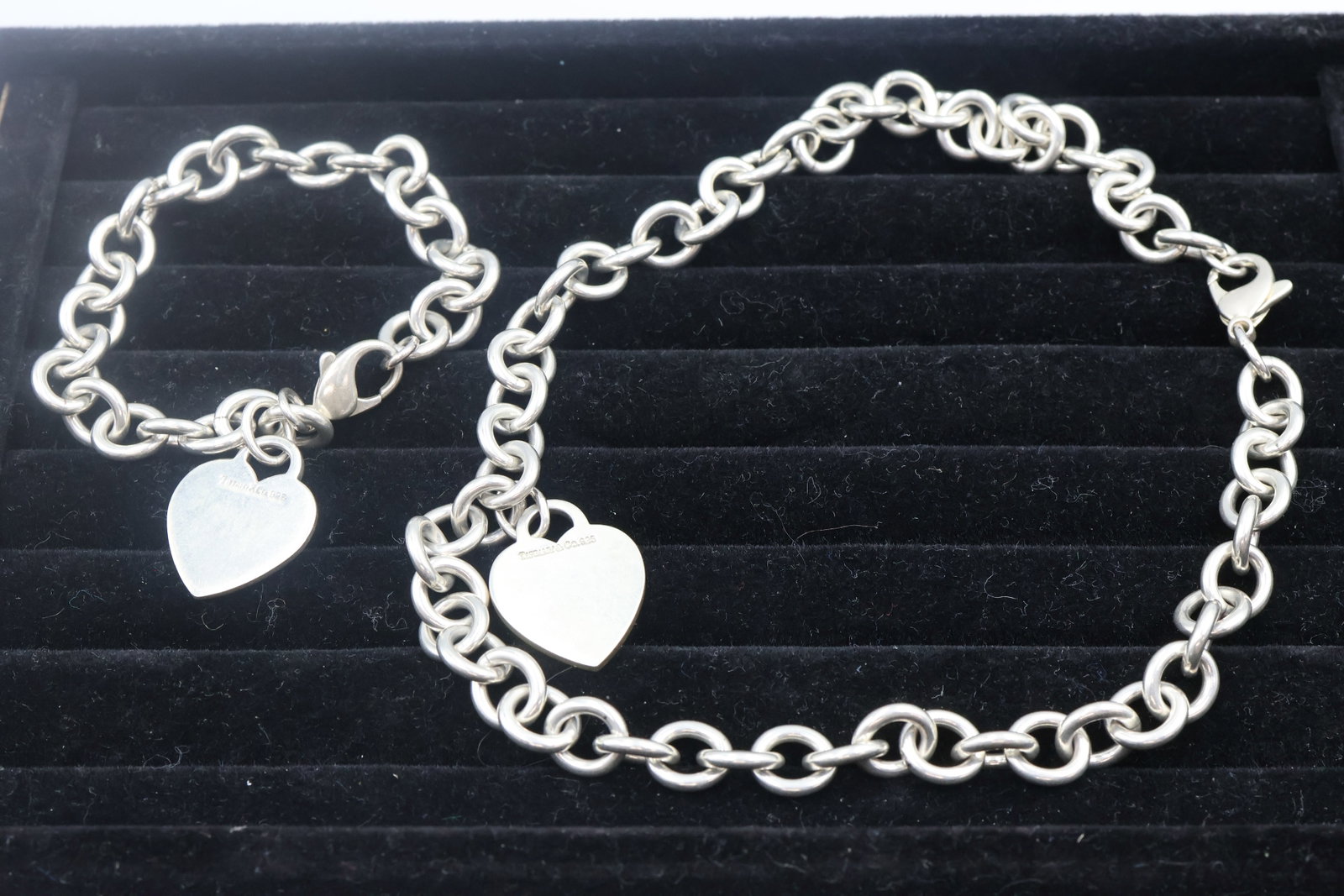 Tiffany & Co Heart Charm Bracelet & Necklace: Classic Tiffany & Co. set comprising a sterling silver bracelet and necklace, each featuring the iconic heart charm motif. A timeless and instantly recognizable pairing showcasing Tiffany’s signatur