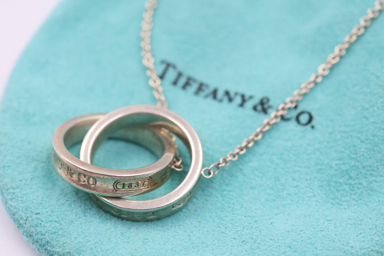 Tiffany & Co 925 Interlocking Circles Pendant: Tiffany & Co. necklace featuring a classic interlocking circles pendant crafted in sterling silver. Total weight: 10.4 grams. Accompanied by a Tiffany & Co. pouch.