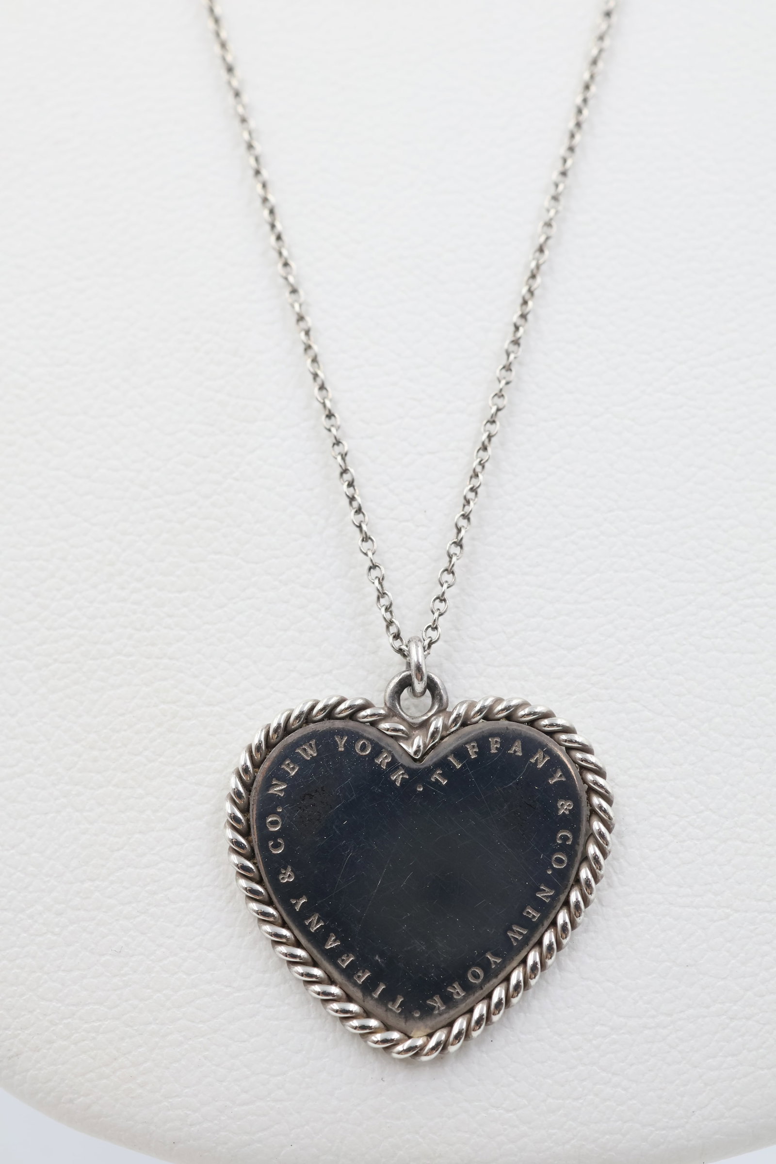 Tiffany & Co 925 Heart Charm Necklace: Tiffany & Co. necklace featuring a classic heart charm with twist border detailing. Measures approximately 22 inches. Total weight: 4.6 grams. Accompanied by a Tiffany & Co. pouch.