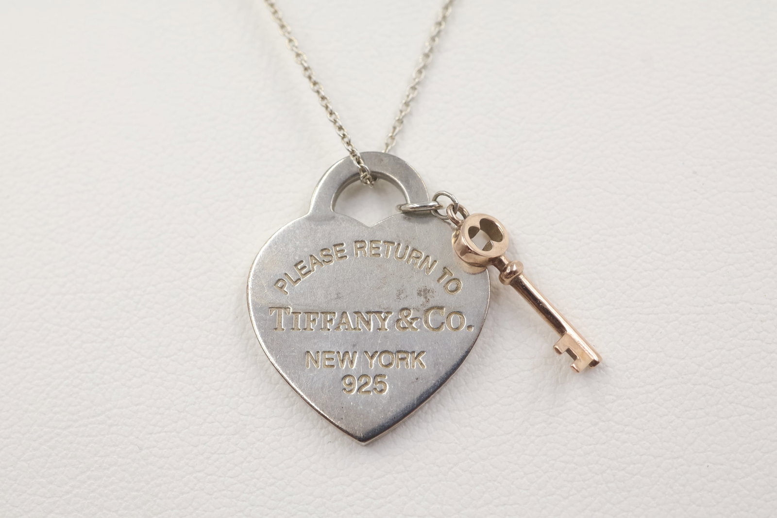Tiffany & Co 925 Heart & Key Charm & Necklace: Tiffany & Co. necklace featuring classic heart and key charms. Total weight: 7 grams. Accompanied by a Tiffany & Co. pouch.