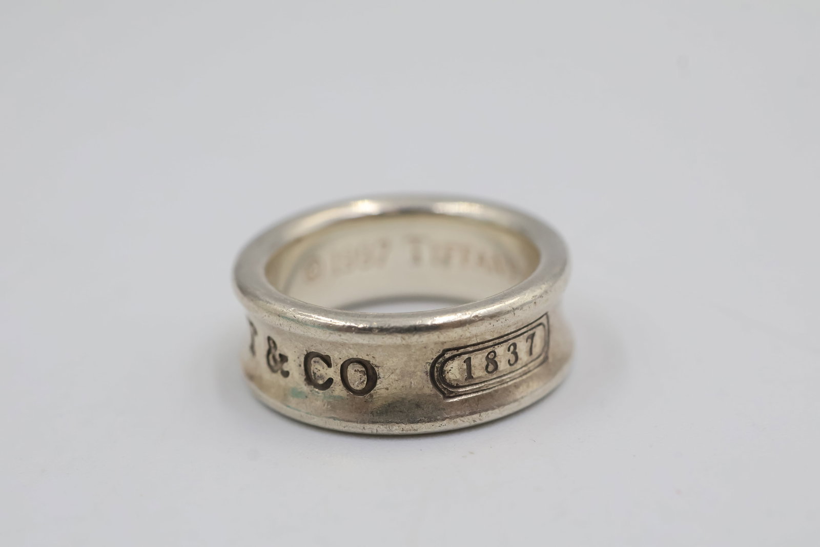 T & Co 1837 Sterling silver Band: Tiffany & Co. 1837 band crafted in sterling silver with signature detailing. Size: 4.5. Total weight: 7 grams. Accompanied by a Tiffany & Co. pouch.
