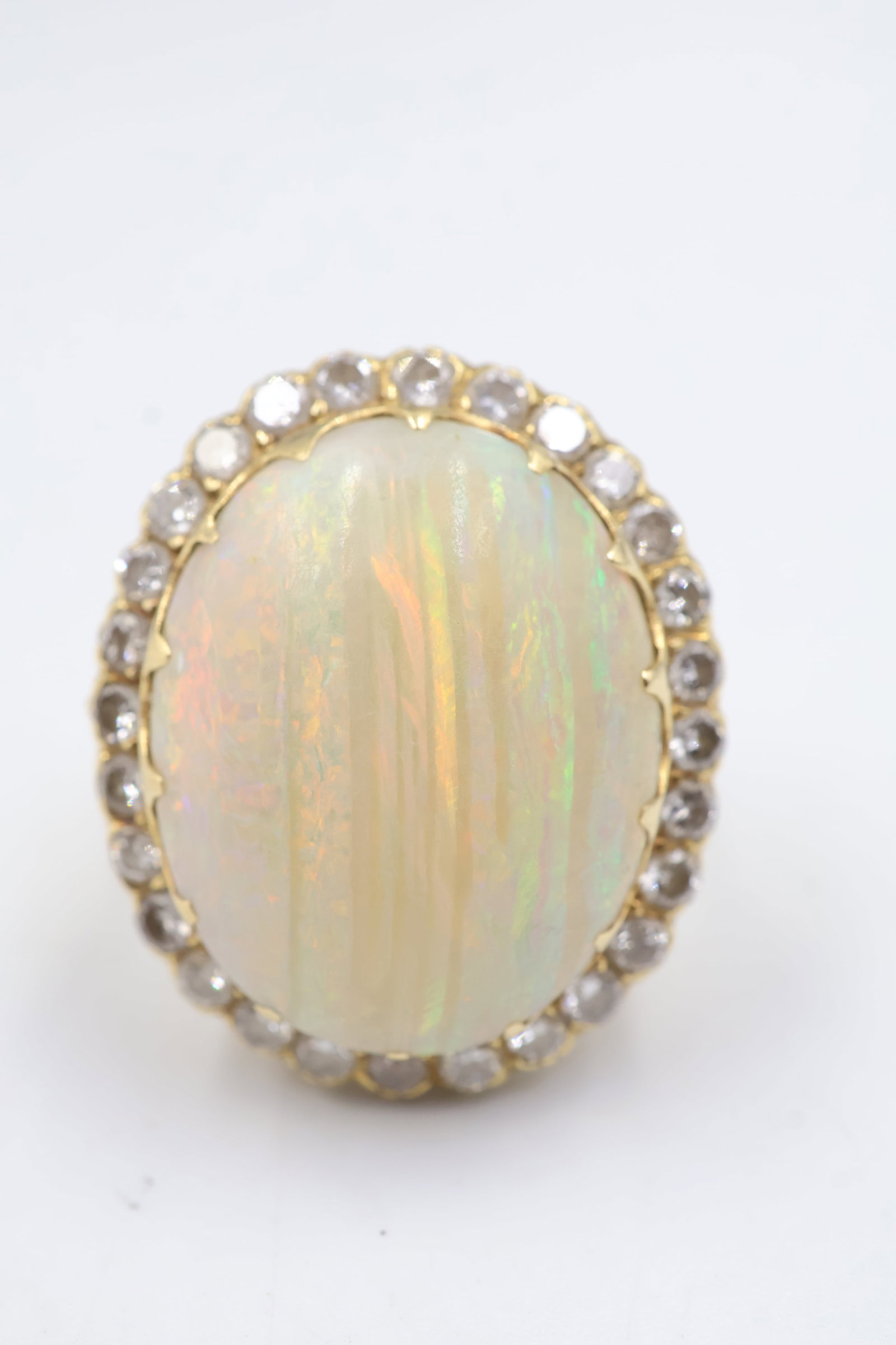 18k Yellow Gold, Diamond & Opal Cocktail Ring: Striking 18k yellow gold cocktail ring featuring a luminous opal surrounded with sparkling diamonds. A bold and elegant statement piece showcasing captivating colour and brilliance. Weight 9.3 grams.