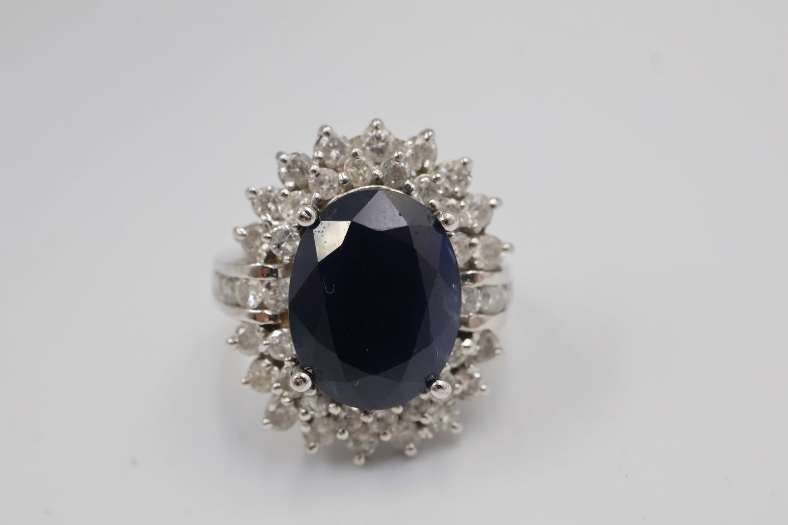 14k White Gold Sapphire & Diamond ring: Elegant 14K white gold ring featuring an oval natural blue sapphire weighing approximately 6.90 carats, accented by 44 round brilliant-cut diamonds totaling approximately 1.54 carats, G–H colour, I1