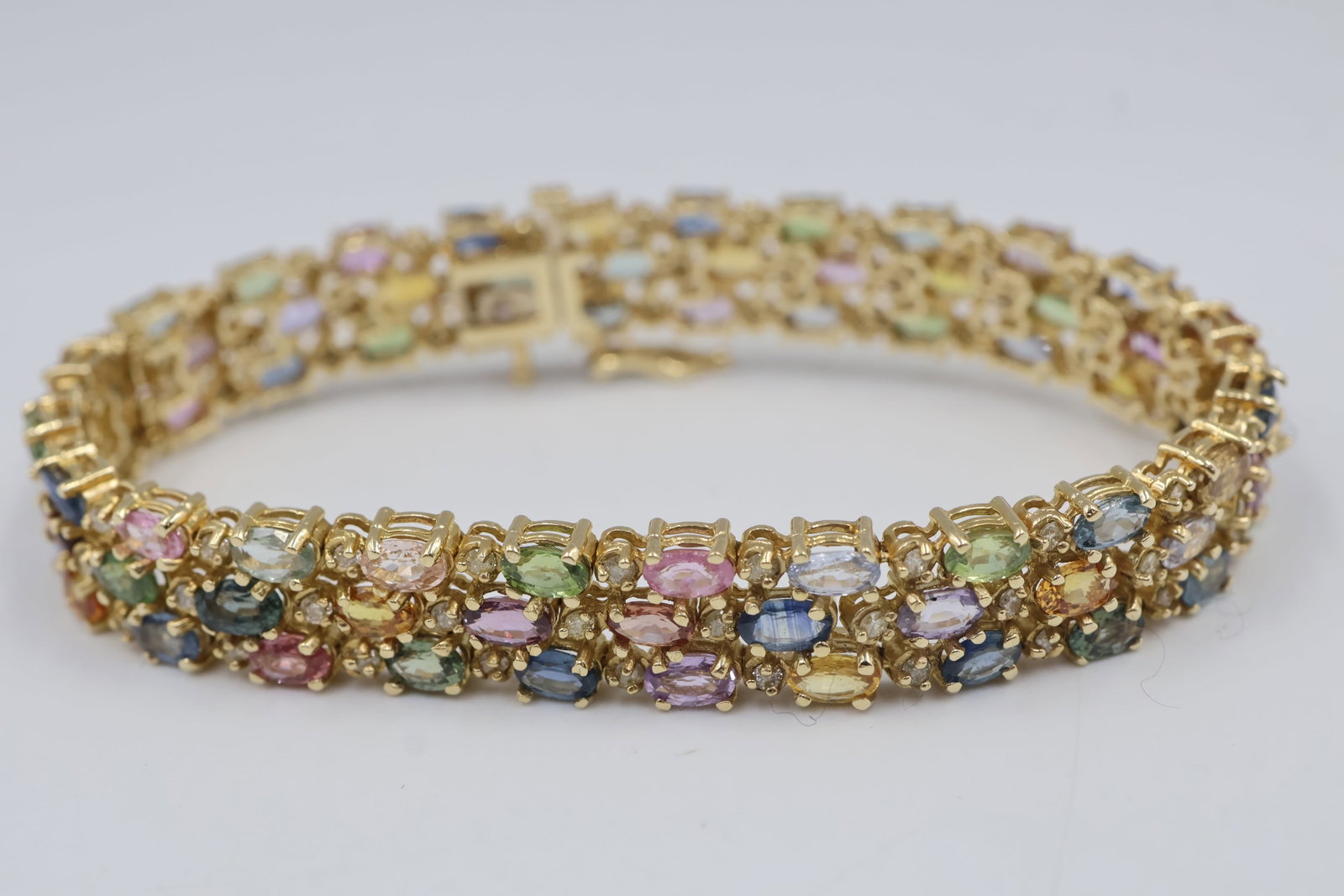 14k Multi Coloured Sapphire Bracelet: Striking 14K yellow gold cluster bracelet featuring 72 oval natural multi-coloured sapphires totaling approximately 21.03 carats, accented by 72 round brilliant-cut diamonds totaling approximately