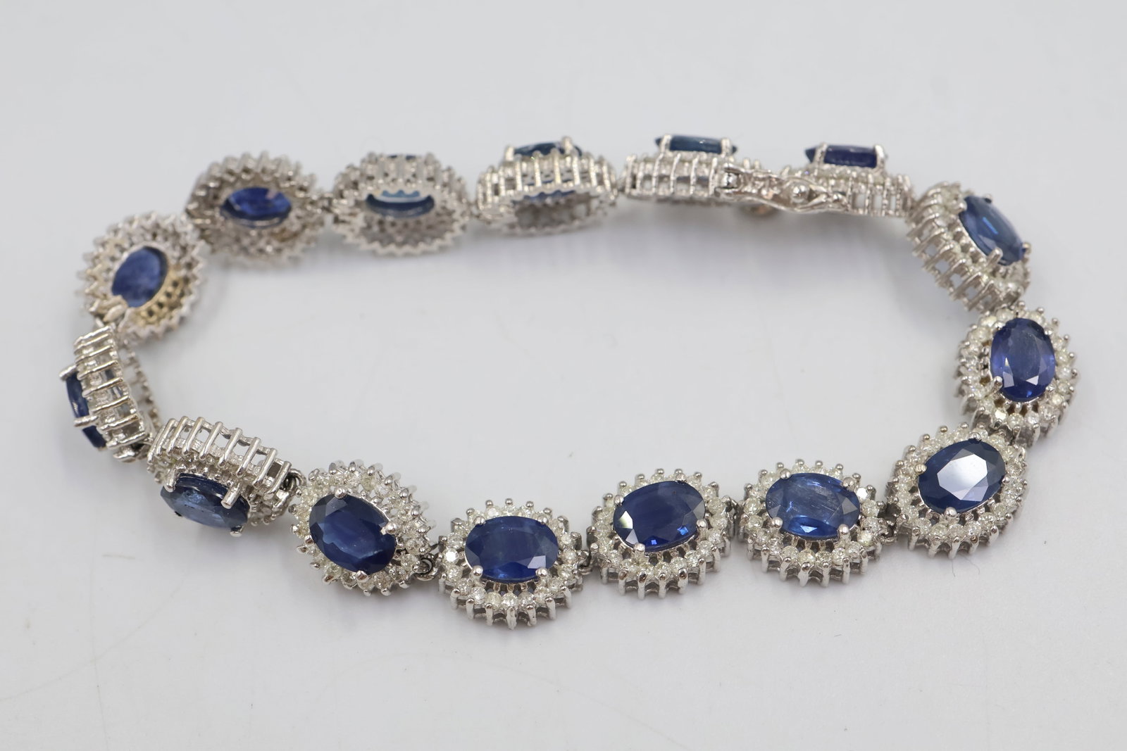 14k Gold Sapphire & Diamond Bracelet: Elegant 14K white gold cluster bracelet featuring 15 oval natural blue sapphires totaling approximately 14.39 carats, accented by 300 round brilliant-cut diamonds totaling approximately 3.45 carats,
