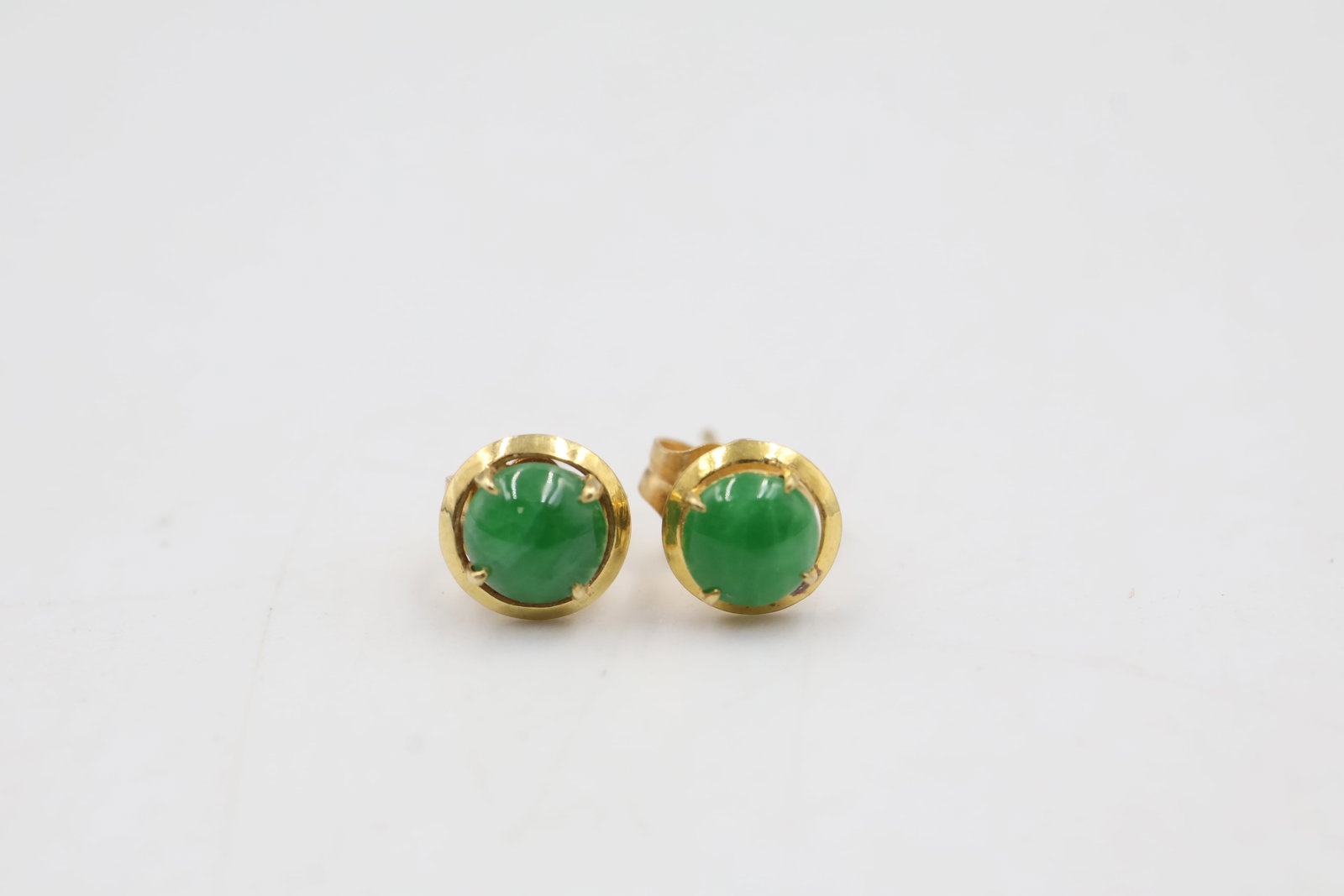 18k Gold & Jade Stud Earrings: Elegant 18K gold stud earrings featuring polished jade accents. Total weight: 0.88 grams.