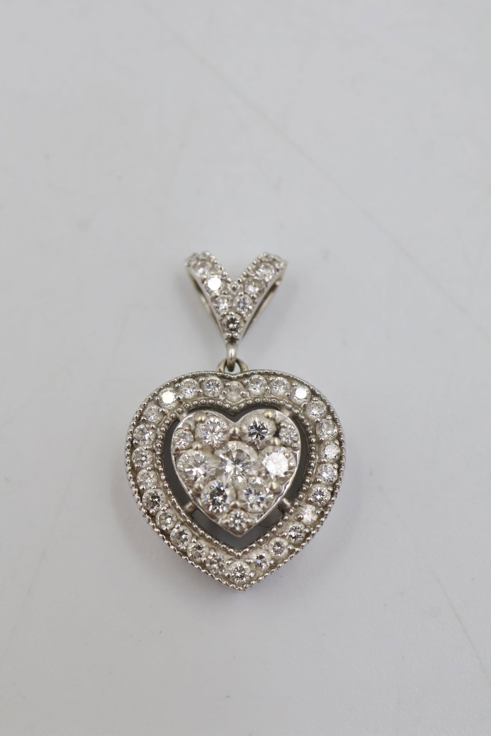 14k White Gold & Diamond Heart Pendant: 14K white gold pendant featuring a classic heart design accented with sparkling diamonds. Total weight: 2.6 grams.