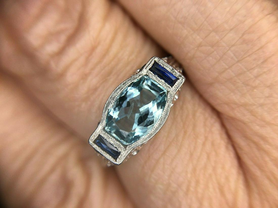 10k White Gold Aquamarine Filigree Ring with Synthetic Sapphires: 10k White Gold Aquamarine Filigree Ring with Synthetic Sapphires Base Metal: Gold Certification: GIA Main Stone Color: Aqua Metal: White Gold Vintage: Yes Era: Art Deco (1915-1935) Material: Metal