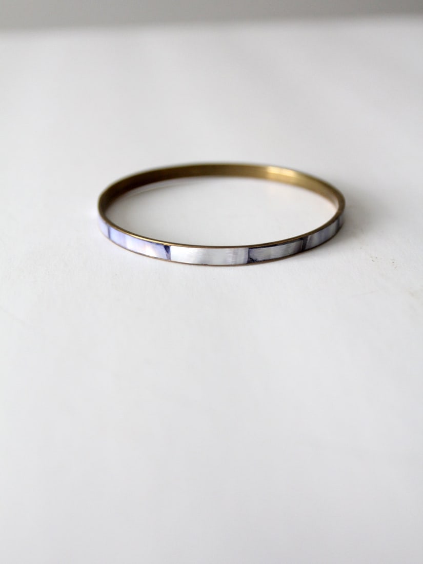 Vintage Mother Of Pearl Blue Bangle: Vintage Mother Of Pearl Blue Bangle This is a vintage slip on bangle. The bracelet features a blue shell inlay across the front and brass tone backing. Great for stacking with other bangles. Length 7 