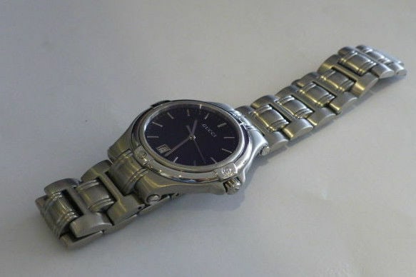 Mens Gucci Watch Stainless Steel Swiss Quartz Movement Black Dial: Mens Gucci Watch Stainless Steel Swiss Quartz Movement Black Dial Features: Date Indices: 12-Hour Dial Non-Numeric Hour Marks Water Resistance: 30 m (3 ATM) Display: Analog Shape: Round Case Material: