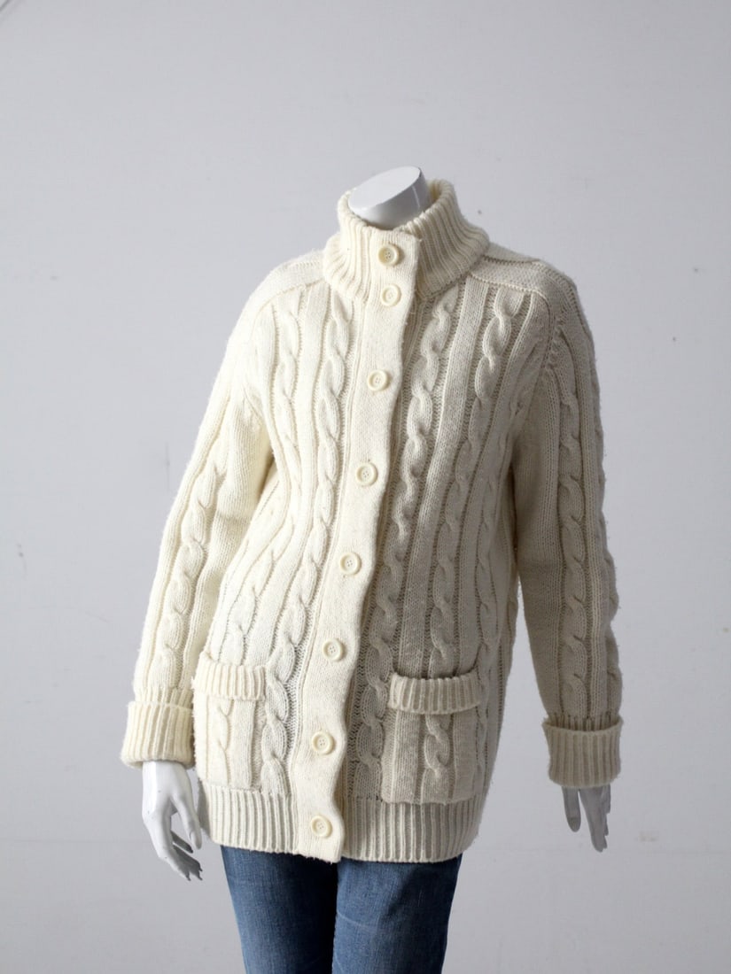 Vintage 70S Sears Cardigan Sweater: Vintage 70S Sears Cardigan Sweater This is a 1970s vintage Sears cable knit cardigan. The cream acrylic knit sweater buttons closed and has a high collar. It has pockets on the waist and rolled cuffs.