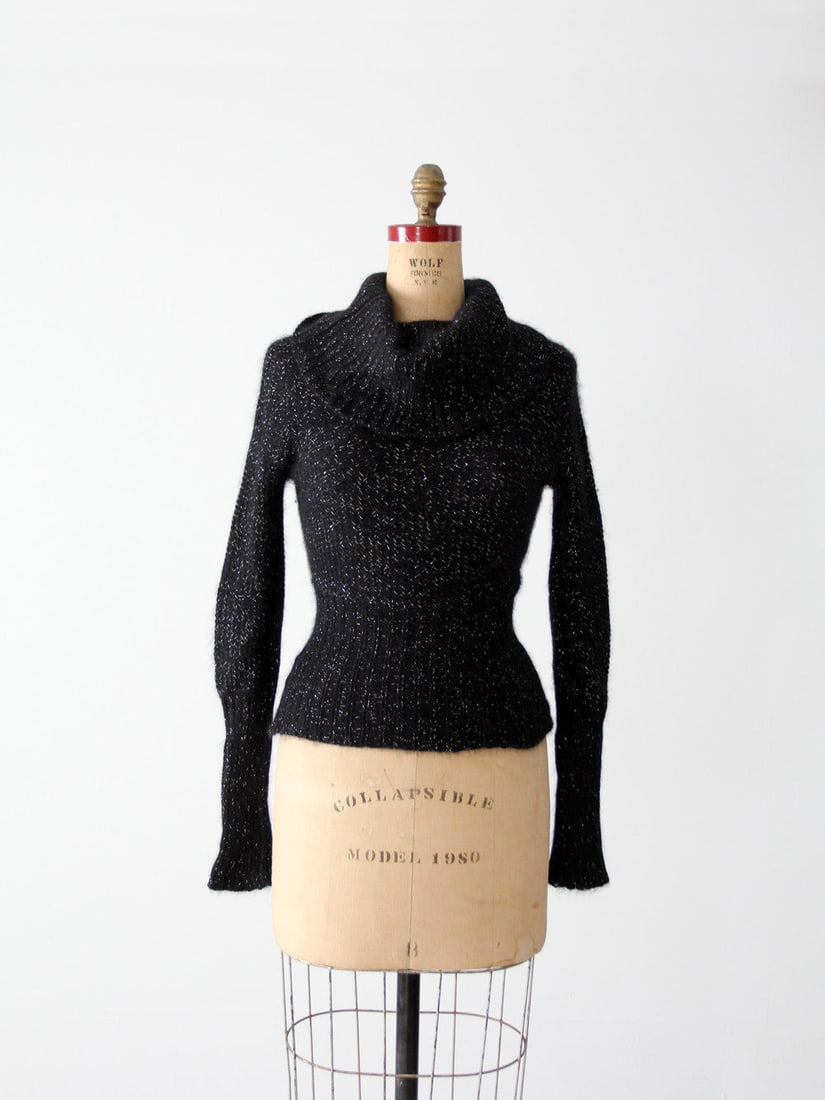 Vintage Angora Cowl Neck Sweater: Vintage Angora Cowl Neck Sweater A late 1980s vintage angora cowl neck sweater. Ultra soft the black knit pullover features metallic silver threaded detailing. It has a big cowl neck and a ribbed wais