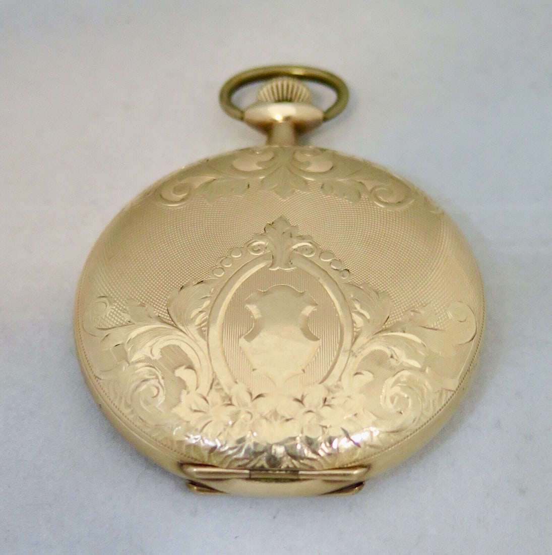 Vintage Waltham Gold Filled Pocket Watch with Engraved Case: This vintage Waltham pocket watch, crafted in the early 20th century, features a gold-filled case beautifully adorned with a floral scroll motif and an etched sea shore scene with a lighthouse. The wh