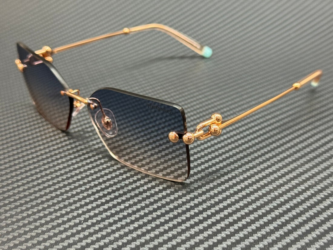 TIFFANY TF3088 Pink Gold Women's Sunglasses with Blue Gradient Lenses: TIFFANY TF3088 Pink Gold Women's Sunglasses with Blue Gradient Lenses Stylish TIFFANY TF3088 sunglasses featuring a pink frame with a geometric design. The lenses are tinted with a blue gradient, offe