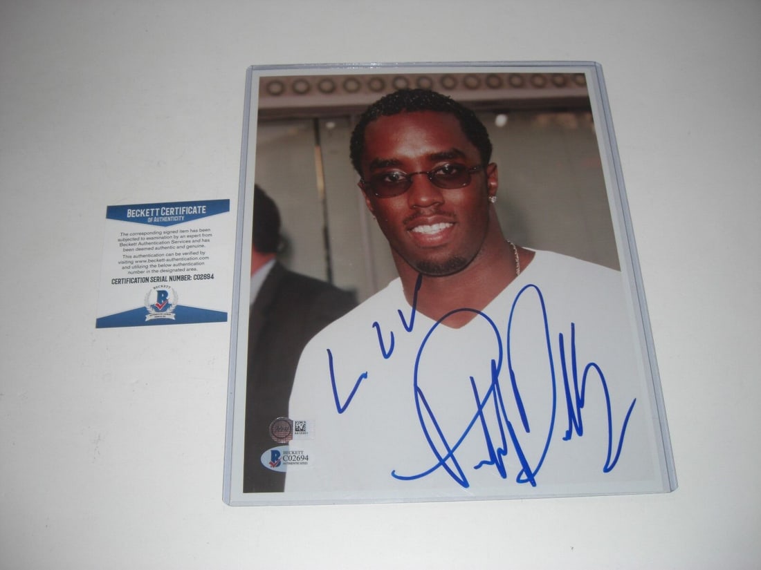 Puff Daddy Signed 8x10 Photo in White Shirt with Beckett COA: Puff Daddy Signed 8x10 Photo in White Shirt with Beckett COA This original 8x10 photo features Puff Daddy, a famous rapper, wearing a white t-shirt and sunglasses. The photo is hand-signed in a styliz