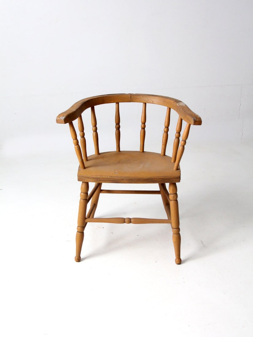 Vintage Wooden Captains Chair with Aged Wheat-Tone Finish: Vintage Wooden Captains Chair with Aged Wheat-Tone Finish This antique wooden captains chair showcases a classic barrel seat design with beautifully aged wheat-tone paint. It features turned spindles