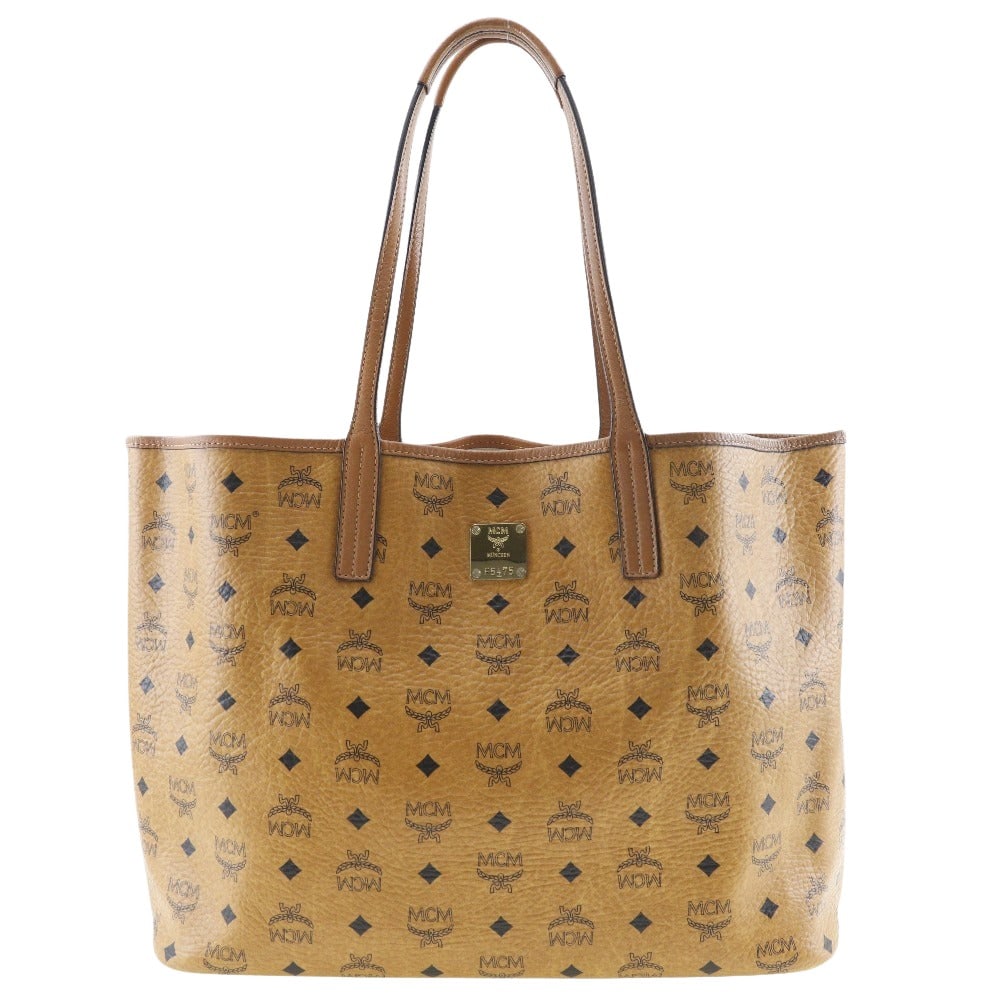 MCM Visetos Tote Bag: MCM Visetos Tote Bag Introducing the MCM Visetos Tote Bag, a statement piece designed for the modern woman. Crafted from iconic Monogram canvas, this tote showcases a contemporary style and luxurious