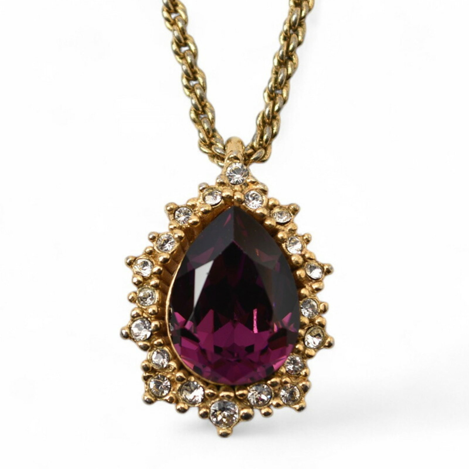 Vintage Christian Dior Gold Teardrop Rhinestone Necklace: Vintage Christian Dior Gold Teardrop Rhinestone Necklace This exquisite Christian Dior necklace showcases a stunning teardrop-shaped purple rhinestone, elegantly encircled by shimmering clear gemstone