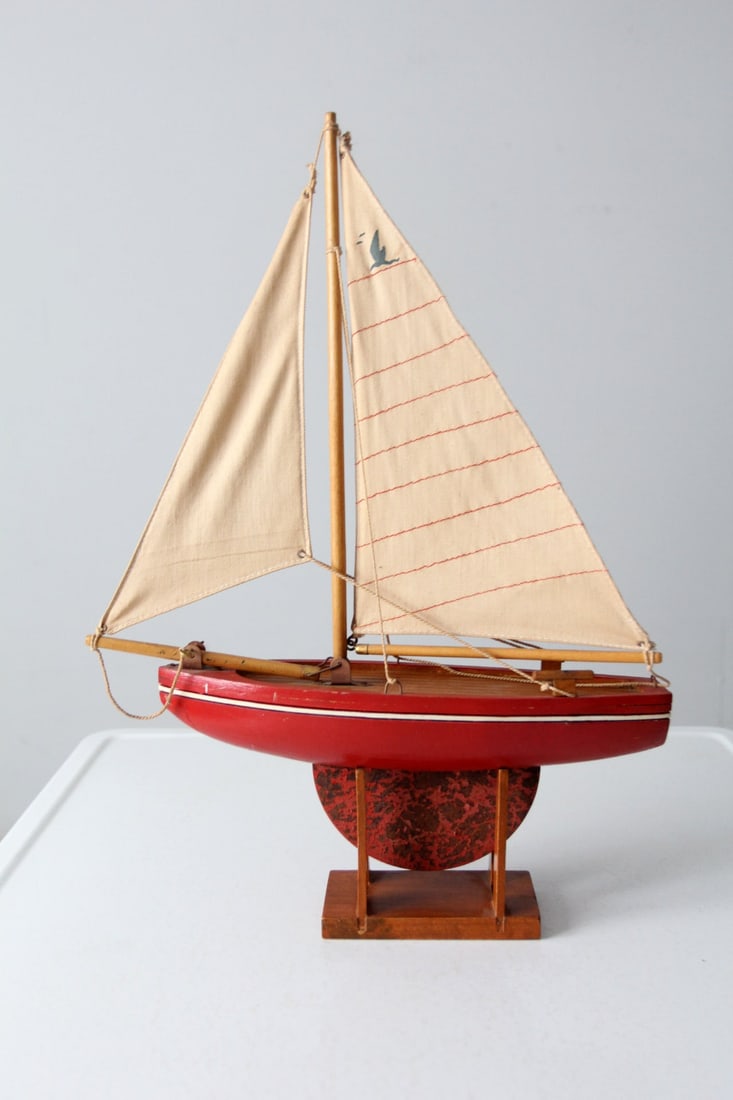 1920s Nautical Wooden Model Sailboat with Iron Keel: 1920s Nautical Wooden Model Sailboat with Iron Keel A model sailboat circa 1920s-1930s. The decorative nautical wooden boat features an iron keel and canvas sails. Perches on a wood stand for display.