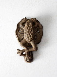 Charming Vintage Cast Iron Frog Door Knocker on Lily Pad: Charming Vintage Cast Iron Frog Door Knocker on Lily Pad This vintage cast iron door knocker showcases a delightful frog seated on a textured lily pad, embodying intricate detail and a rustic aged