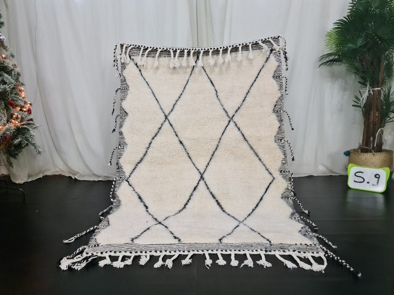 Authentic Moroccan Berber Wool Rug 3.28 x 5 Feet with Geometric Frame: Authentic Moroccan Berber Wool Rug 3.28 x 5 Feet with Geometric Frame Introducing an authentic Soft White Handmade Moroccan Berber Wool Rug, featuring a striking black geometric pattern and an engrave