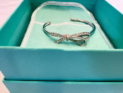 Tiffany & Co 18K White Gold Diamond Bow Cuff Bracelet with Bag and Box: Tiffany & Co 18K White Gold Diamond Bow Cuff Bracelet with Bag and Box This exquisite cuff bracelet by Tiffany & Co. showcases a stunning bow design crafted from 18K white gold and adorned with diamon