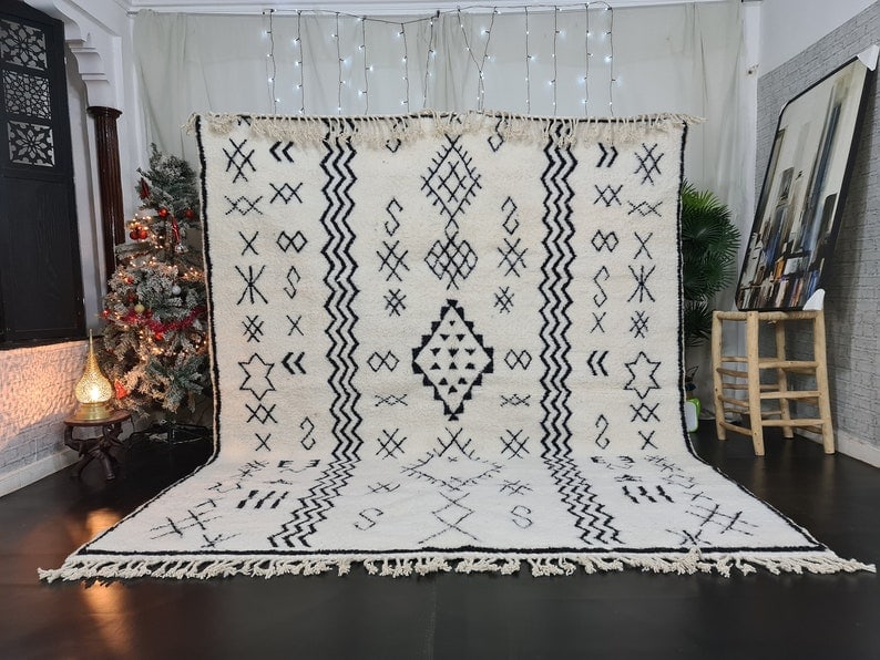 Handmade Moroccan Berber Wool Rug 9.84 x 6.56 Feet: Handmade Moroccan Berber Wool Rug 9.84 x 6.56 Feet Experience the elegance of this stunning soft white handmade Moroccan Berber wool rug, featuring intricate patterns and symbols in black. Crafted by 