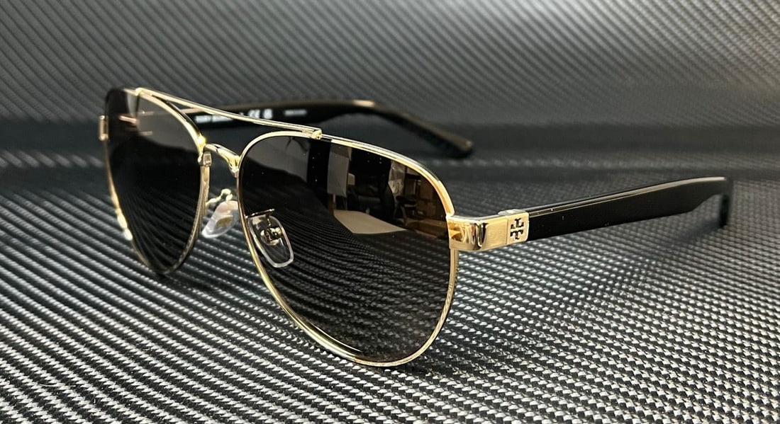 Tory Burch TY6070 Gold Aviator Sunglasses with Gray Gradient Lenses: Tory Burch TY6070 Gold Aviator Sunglasses with Gray Gradient Lenses Elevate your style with these Tory Burch TY6070 sunglasses, featuring a chic aviator design. The lightweight metal frame is finished