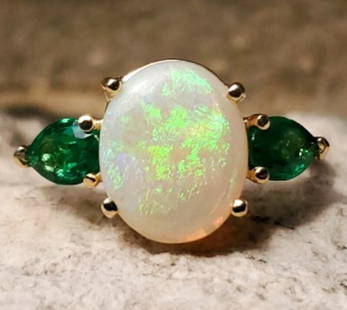 Stunning 18k Yellow Gold Opal Emerald Ring 1.76ct Size 9.25 GIA Certified: Stunning 18k Yellow Gold Opal Emerald Ring 1.76ct Size 9.25 GIA Certified This exquisite 18k yellow gold ring showcases a stunning 1.76ct genuine natural opal surrounded by two fine quality emeralds.