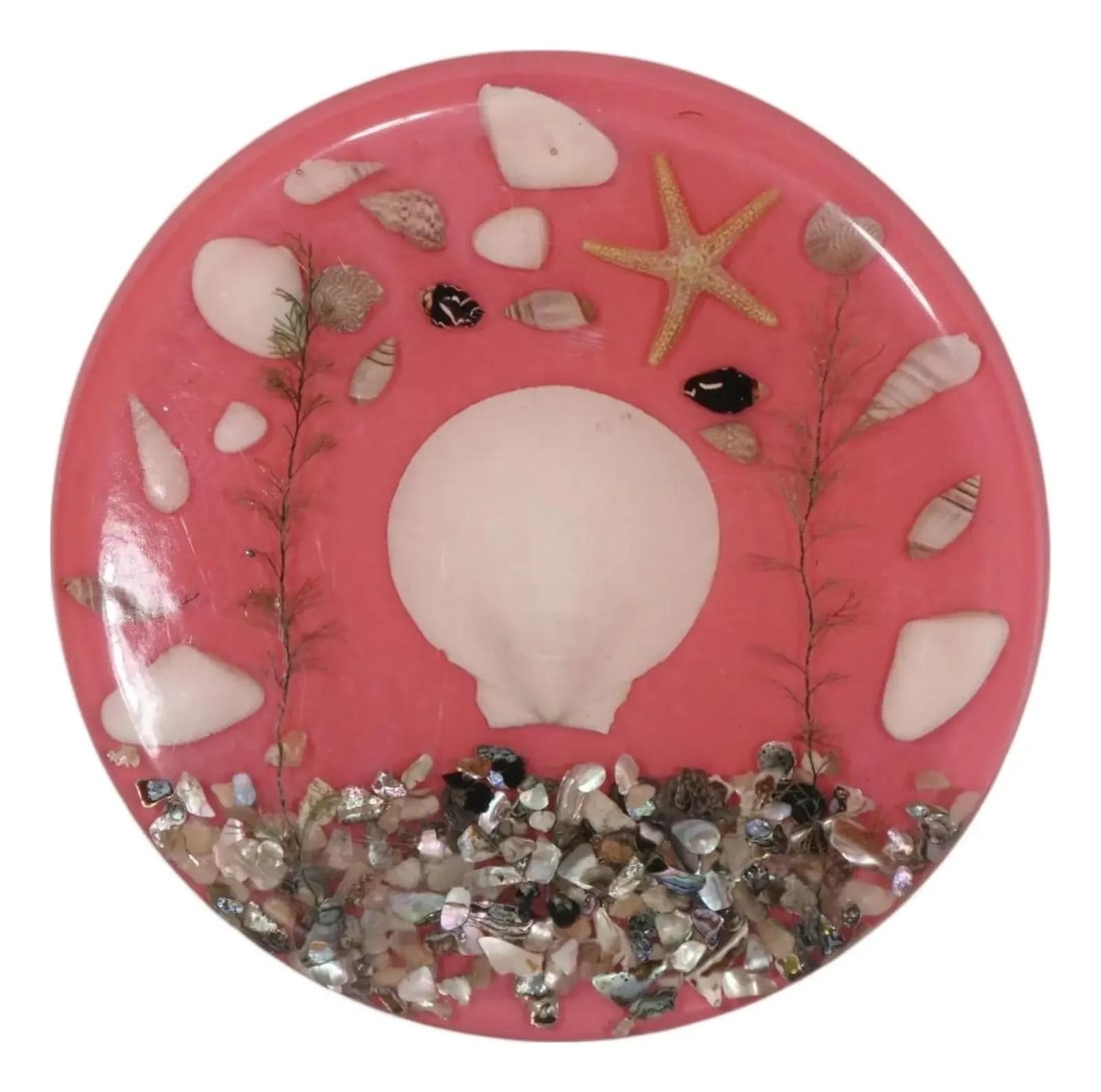 Vintage Lucite Trivet with Encased Sea Shells in Rose: Vintage Lucite Trivet with Encased Sea Shells in Rose This charming vintage Lucite trivet features beautifully encased sea shells set against a delicate pink background. It is supported by three clear
