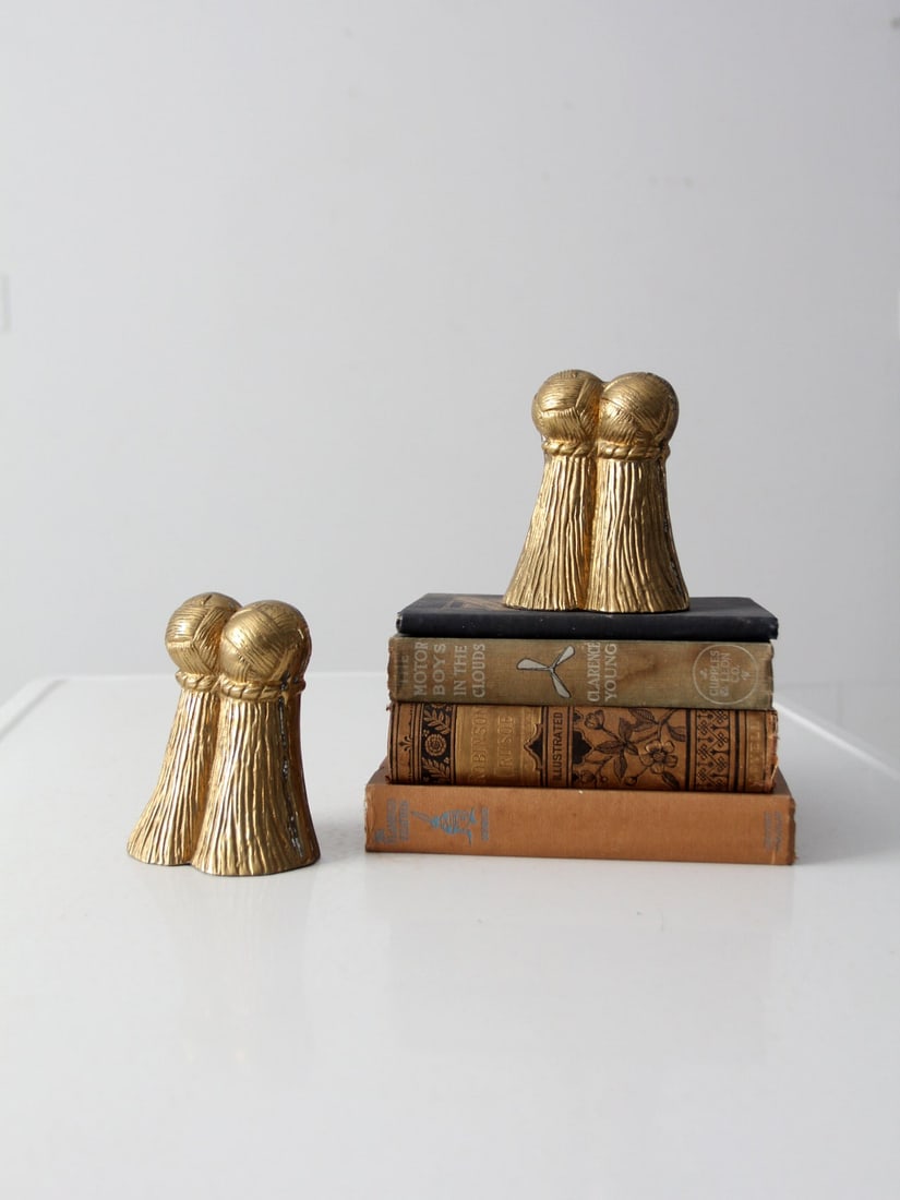 1970s Vintage Brass Tassel Bookends Hollywood Regency Pair: 1970s Vintage Brass Tassel Bookends Hollywood Regency Pair This elegant pair of vintage brass bookends, dating back to the 1970s, showcases a distinctive Hollywood Regency style with a decorative tass