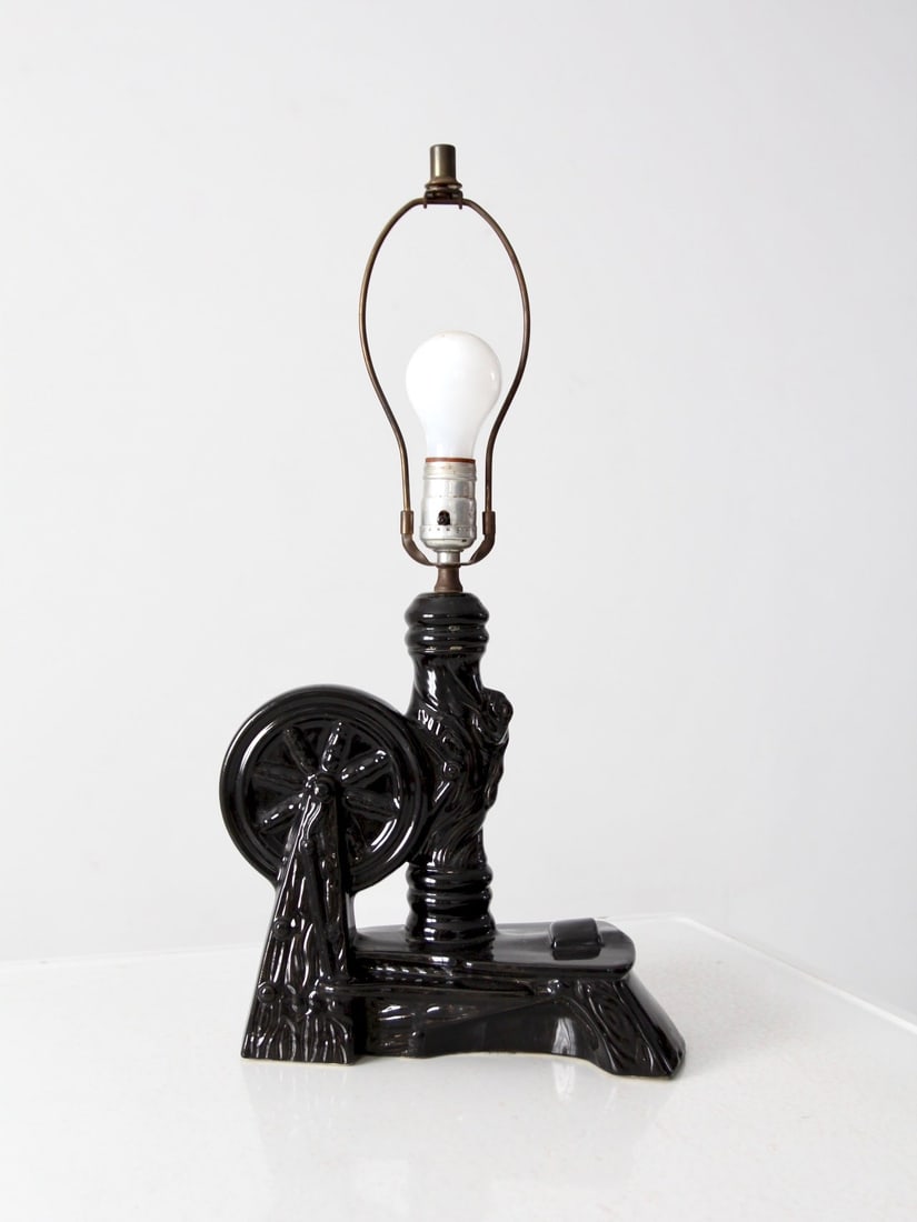 Mid-Century Black Ceramic Table Lamp with Western Base: Mid-Century Black Ceramic Table Lamp with Western Base This mid-century ceramic table lamp showcases a sleek black design with a western-themed base, complemented by a simple brass harp and finial. It