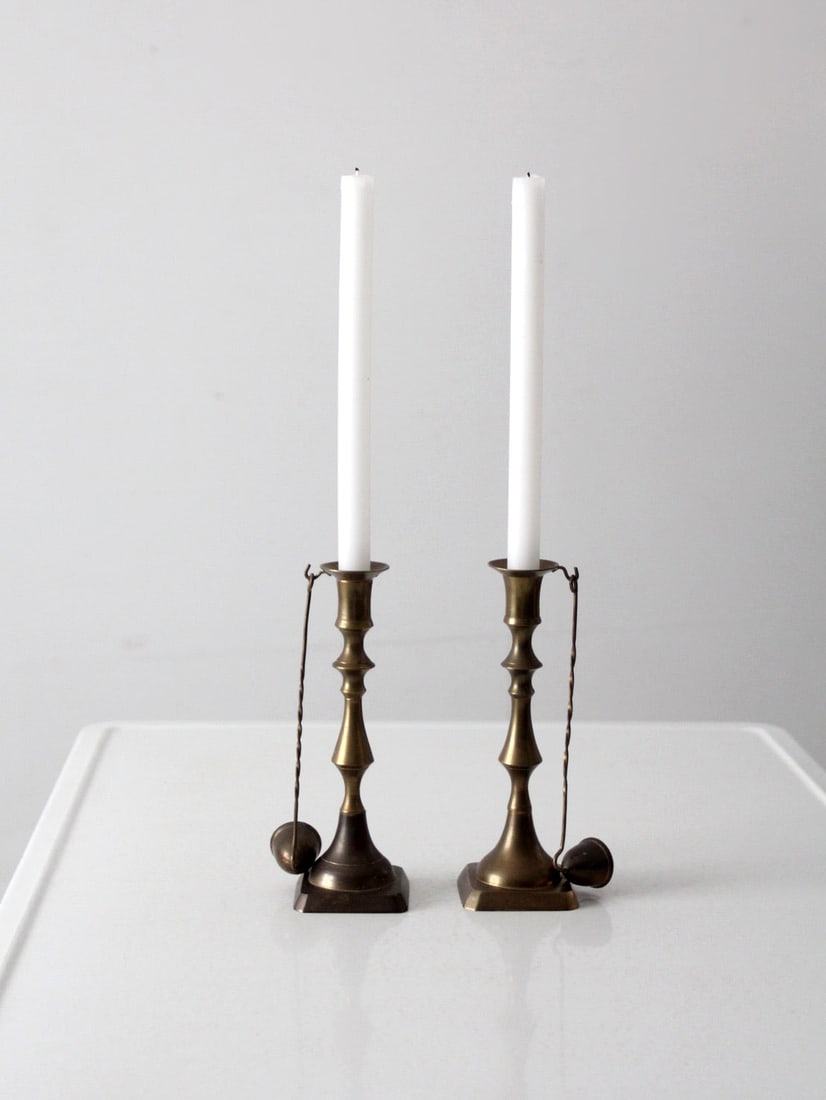 Antique Brass Candlestick Holders Pair with Hanging Snuffers: Antique Brass Candlestick Holders Pair with Hanging Snuffers This exquisite pair of antique brass candlestick holders showcases a traditional baluster style, complete with square bases and hooks desig