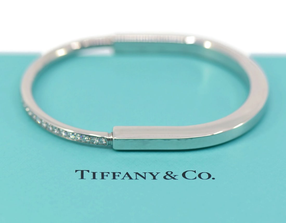 Tiffany & Co 18K White Gold Lock Diamond Bangle Bracelet: Tiffany & Co 18K White Gold Lock Diamond Bangle Bracelet This exquisite Tiffany & Co. bracelet features a stunning lock design crafted from high-quality 18K white gold. The bangle style is adorned wit