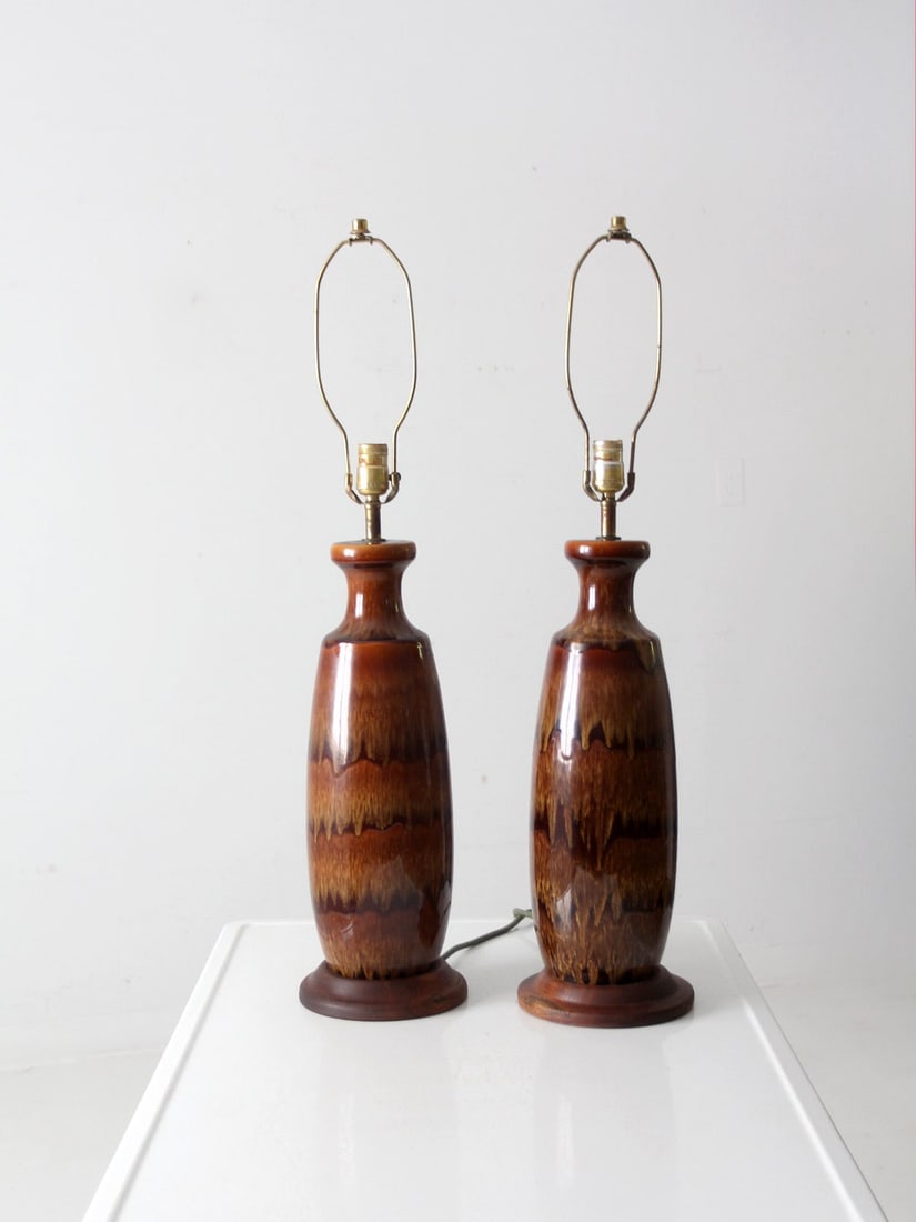 Vintage Mid Century Pottery Lamps Pair with Wooden Bases: Vintage Mid Century Pottery Lamps Pair with Wooden Bases This exquisite pair of mid 20th century pottery lamps showcases a warm ceramic finish complemented by elegant wooden bases and brass harps. Eac
