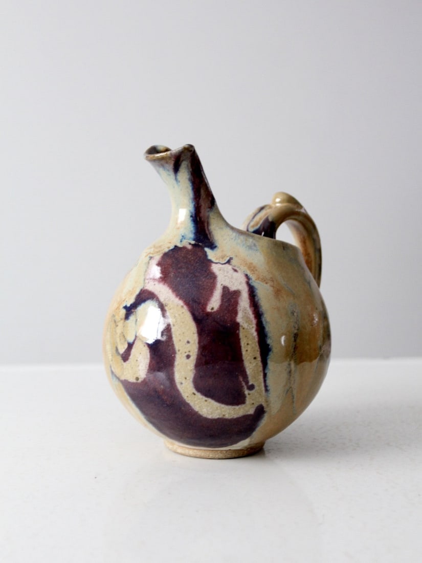 Handcrafted Mid-Century Ceramic Pitcher with Speckled Glaze: Handcrafted Mid-Century Ceramic Pitcher with Speckled Glaze This handcrafted ceramic pitcher is a stunning example of mid-century studio pottery design. Its rounded, bulbous shape is beautifully compl