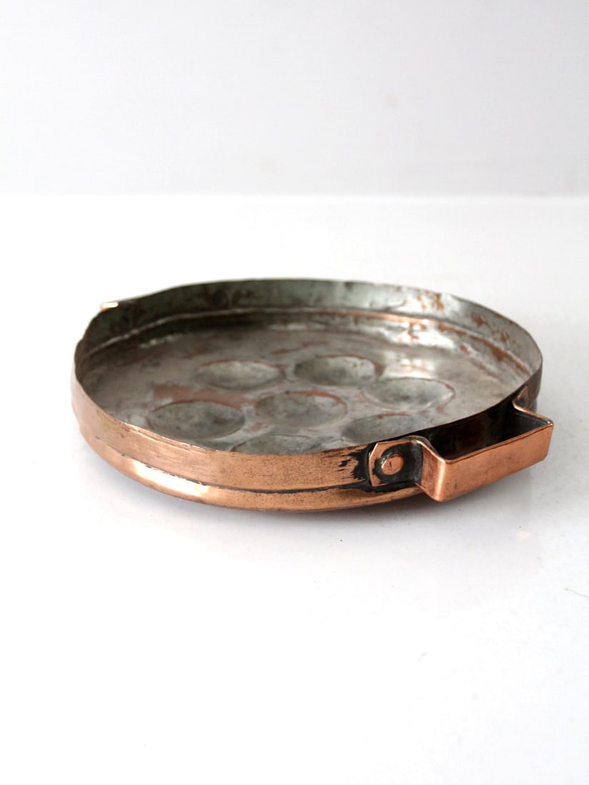 Vintage Hand-Hammered Copper Escargot Pan with Tin Lining: Vintage Hand-Hammered Copper Escargot Pan with Tin Lining Explore this exquisite antique copper escargot pan, which doubles as an egg poacher. This hand-hammered piece showcases a beautiful tin lining