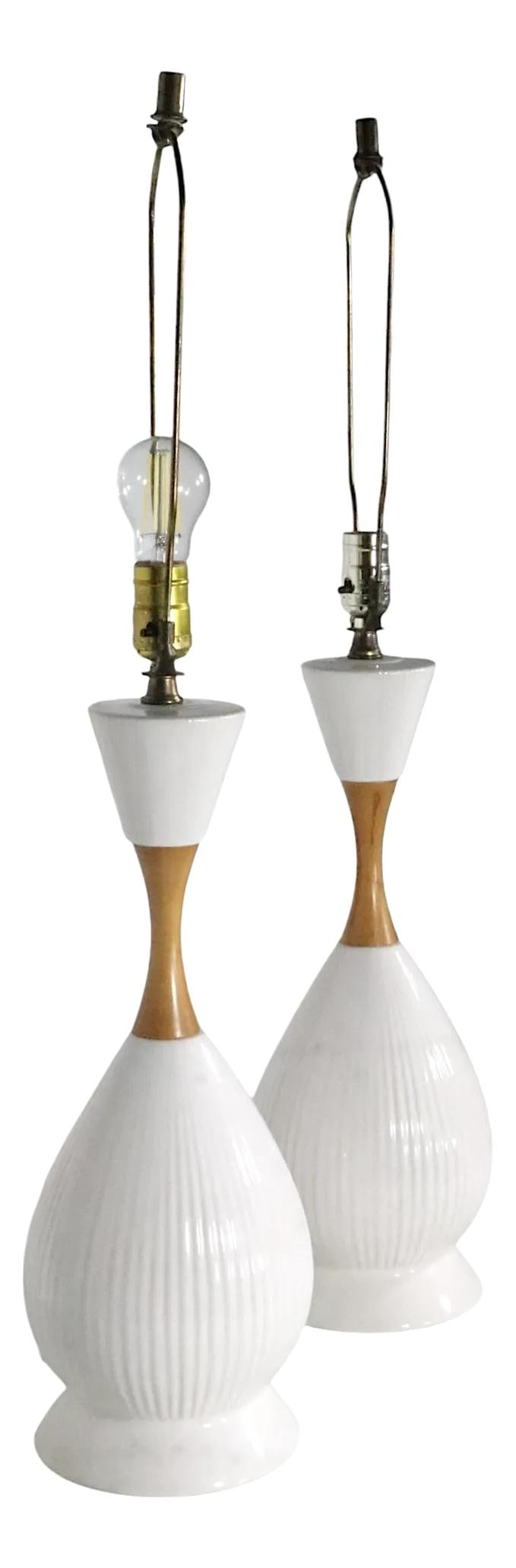 Elegant Pair of Mid Century Ceramic Wood Table Lamps: Elegant Pair of Mid Century Ceramic Wood Table Lamps This elegant pair of mid-century table lamps showcases a unique bowling pin form, blending white ceramic and wood materials. The lamps feature a ri