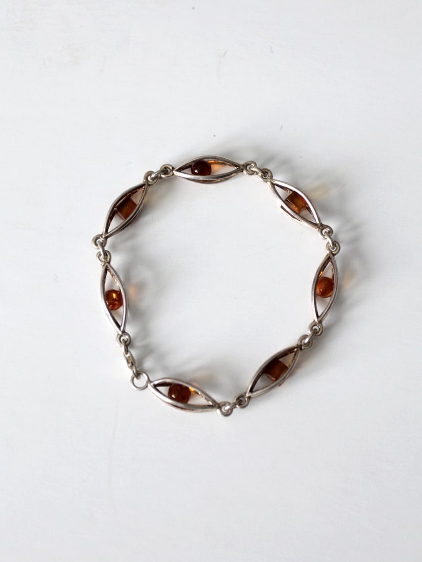Vintage Beaded Amber Bracelet in Silver Tone with Lobster Claw Closure: Vintage Beaded Amber Bracelet in Silver Tone with Lobster Claw Closure This vintage beaded bracelet showcases beautiful amber-colored beads set in silver-tone casings. The chain link design is complem